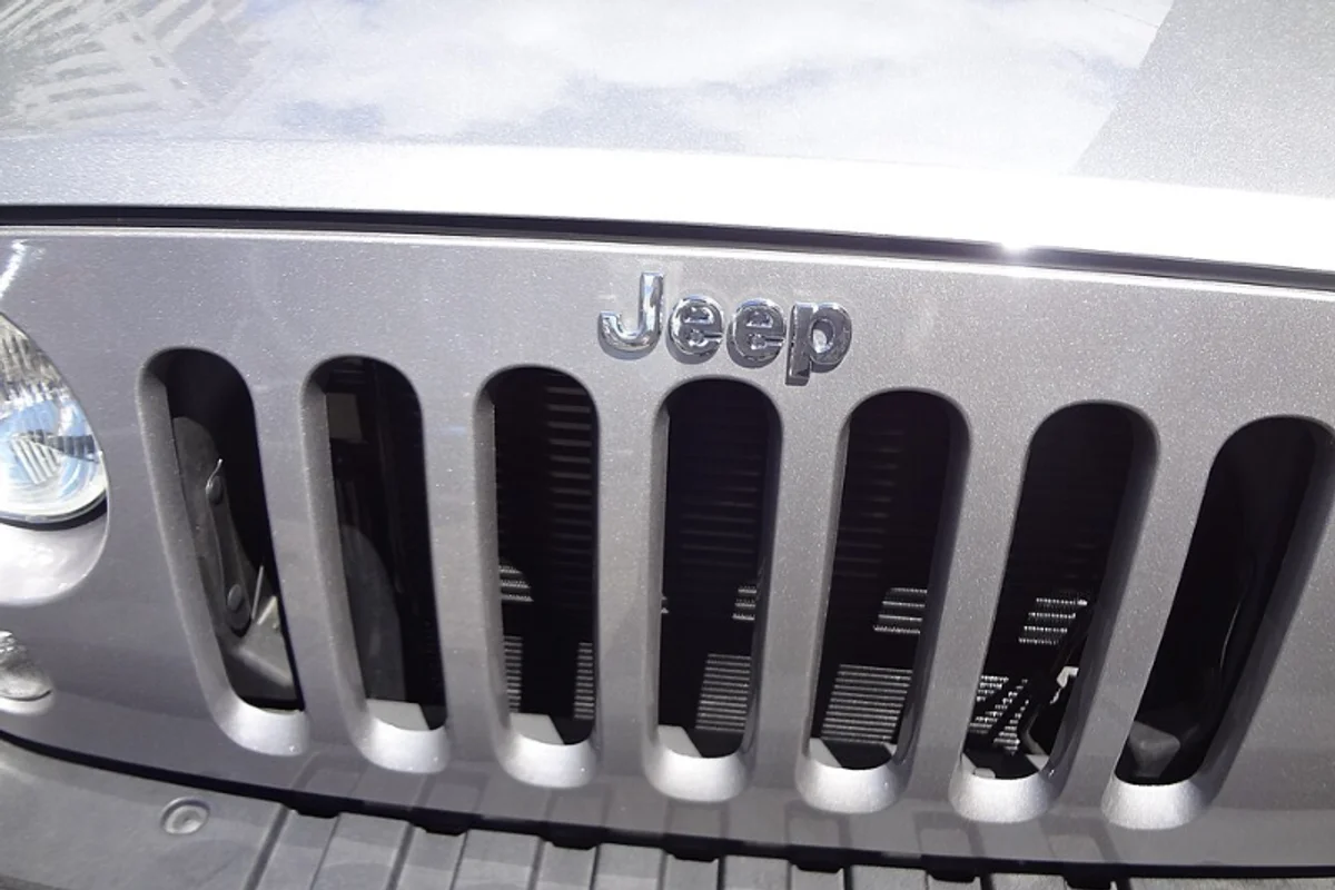 Jeep vehicle badge showing the Helvetica Bold wordmark in chrome on a rugged grille