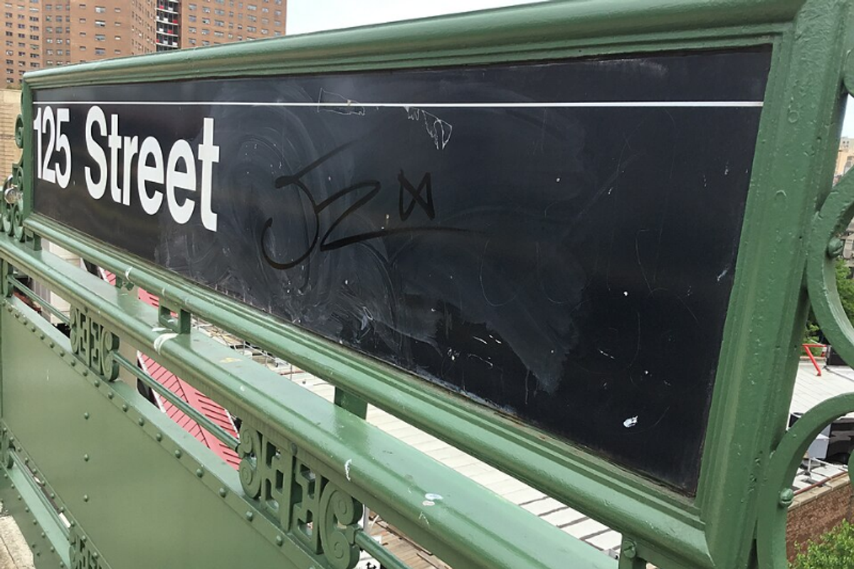 NYC Subway station sign in white Helvetica Medium on a black background with colored route bullets